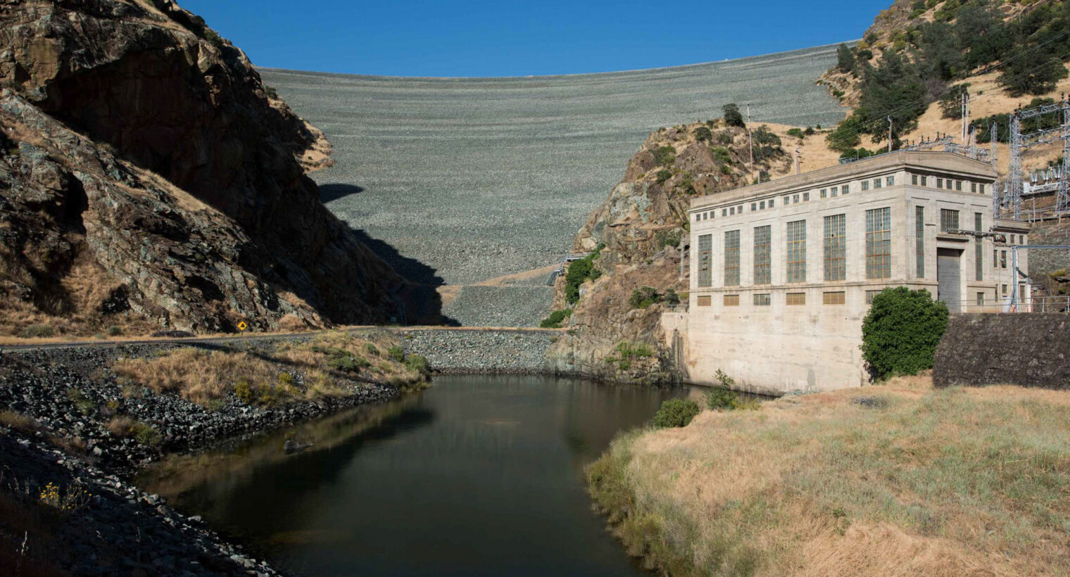 Photos shows New Melones Dam with blue sky